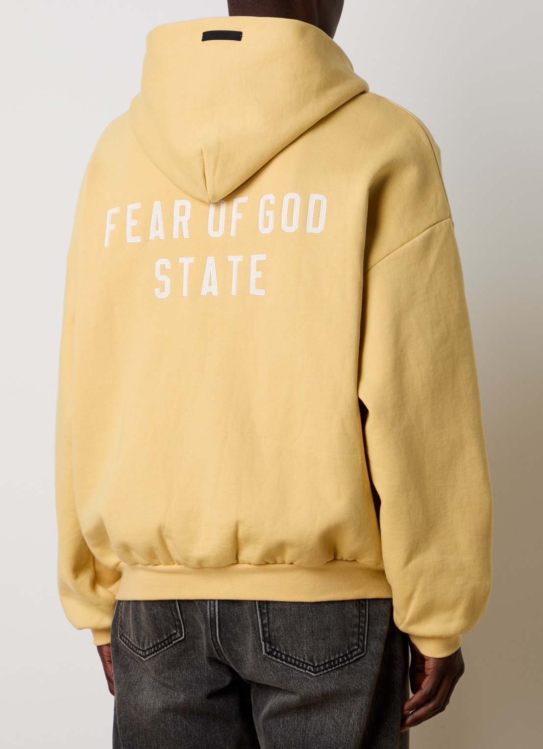 Fear of God Essentials Sweatvest met backprint en capuchon - detail okergeel