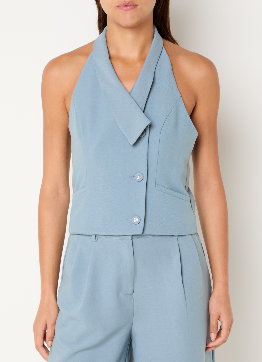 NIKKIE Alani mouwloze blazer met paspelzakken - detail lichtblauw