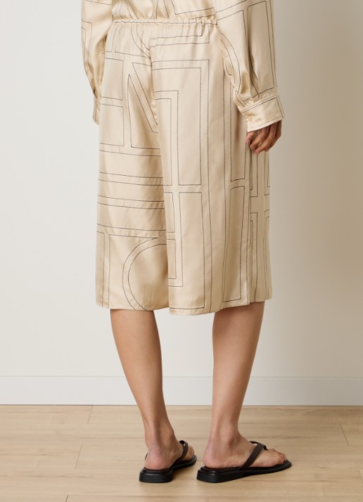 TOTEME Low waist wide fit culotte van zijde met logoprint borduring - achterkant vanillegeel
